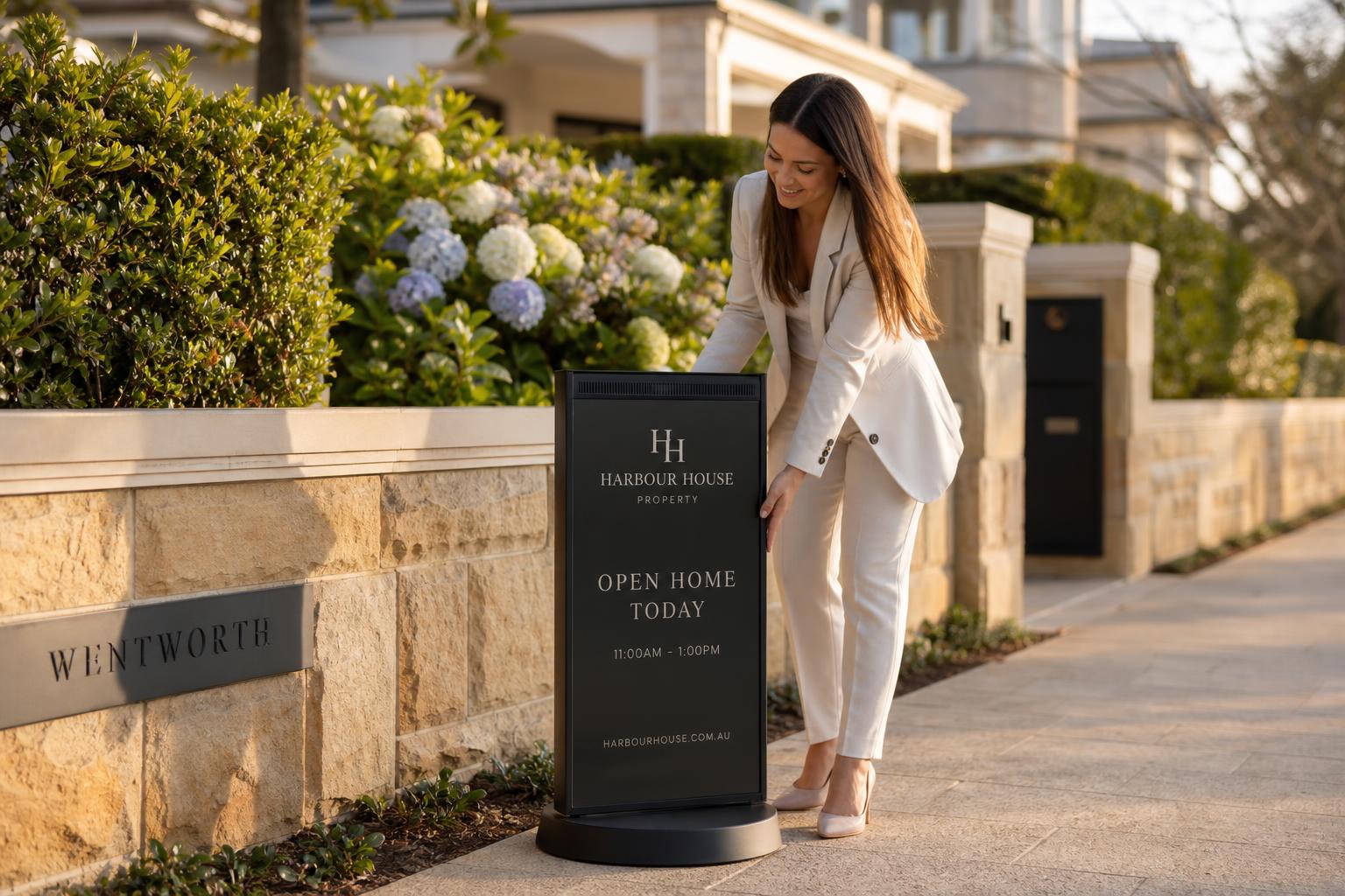 A Curb Media digital directional sign — LED panel — installed outside a contemporary home at golden hour.